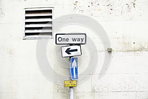 One way directional arrow sign against white wall background