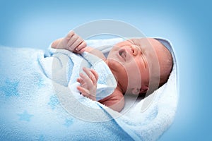 One week old crying baby in blanket on white background