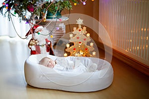 One week old newborn baby girl sleeping near Christmas tree