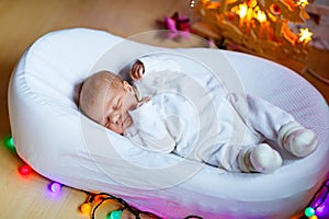 One week old newborn baby girl sleeping near Christmas tree