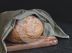 One wheat round bread with fiber on a black background.