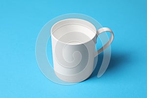 One white ceramic mug on light blue background