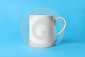 One white ceramic mug on light blue background