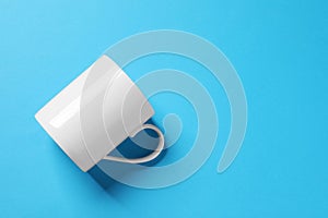 One white ceramic mug on light blue background, top view. Space for text
