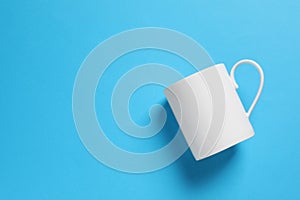 One white ceramic mug on light blue background, top view. Space for text