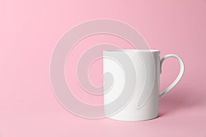 One white ceramic mug on pink background. Space for text