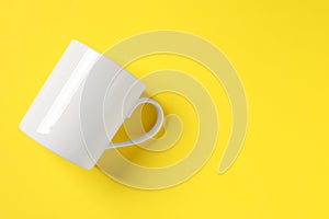 One white ceramic mug on yellow background, top view space for text