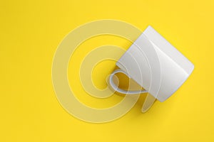 One white ceramic mug on yellow background, top view. Space for text