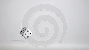 One white dice in super slow motion rebounding and turning on the grey floor