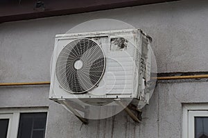 One white dirty air conditioning fan hanging on a gray wall