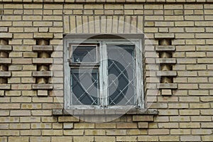 One white old wooden window with iron bars on the brown brick wall