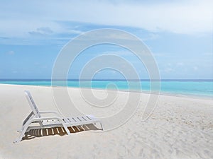 One white plastic beach chair on white sand beach with bright clear blue sky and colorful sea water.