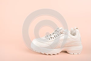 One White sneaker isolated on pastel background. Clean new trendy sneaker on pink background. sport shoes concept