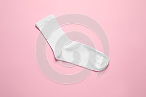 One white sock on pink background, top view