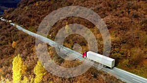 One white truck driving along the freeway amidst a forest in the mountains. Aerial drone view