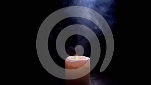 One White Wax Candle Burning in a Cloud of Thick Blue Smoke on Black Background