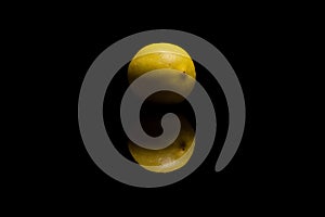 One whole isolated yellow lemon with watter drops on black background