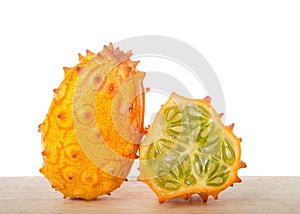 One whole one half kiwano fruit on wood table isolated