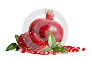 One whole and part of a pomegranate with pomegranate seeds and leaves