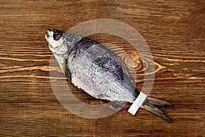 One whole salted sun-dried bream with label on tail on wooden background