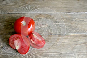 One whole and several cut tomatoes red, close-up  on brown wood backgroun