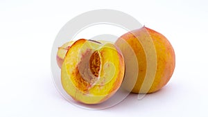 One whole and two halves with the pit of peach fruits. Rotating on the turntable. Isolated on the white background