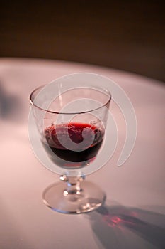 one wine glass with red wine standing on white table