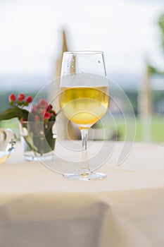 One wineglass with white wine on table with tablecloth