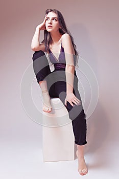 One Winsome Sexy Girl With Colorful Hair Style in Violet Nightie and Black Pants On Wooden Prop On Gray Background as Fashion