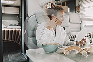 One woman apply cream on face for skin care beauty daily treatment inside a modern camper van during vanlife lifestyle or travel