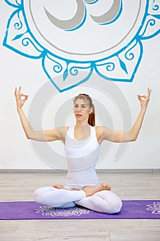 One woman is doing lotus posture with her hands up and Om sign