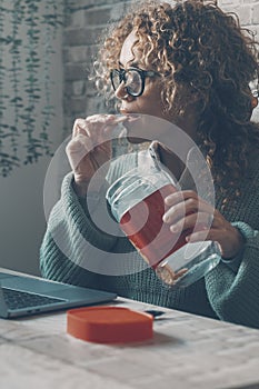 One woman at home using laptop and eating cookies from the box. Concept of bad nutrition food habits lifestyle female people and