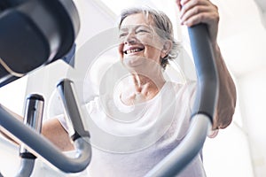 One woman mature or senior at the gym training and doing exercise in on a machine - active pensioner lifestyle and concept