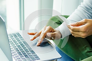One woman online shops with credit card in left hand