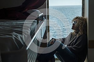 One woman passenger inside cabin boat cruise ferry having relax sitting near the window with ocean sea in background outside.