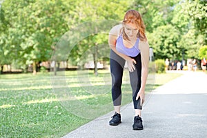 One woman runner hold her injured calf and ankle outdoor