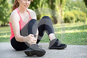 One woman runner hold her injured calf and ankle outdoor