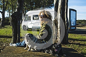 One woman sitting on the ground with her two best friends dogs pug in travel stop with alternative house vanlife motorhome camper