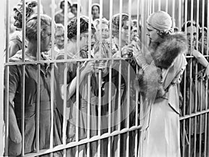 One woman standing in front of a jail talking with a group of women