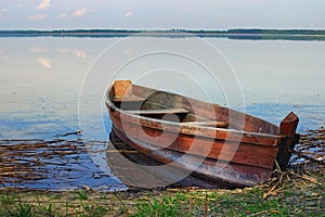 One wooden fishing boat on bank of the lake. Spring landscape photo. Lake Svityaz. Volyn region. Ukraine