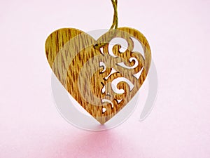 One wooden heart with patterns isolated on pink background.