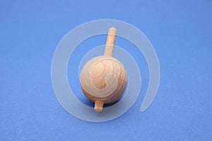 One wooden spinning top on blue background, closeup. Toy whirligig