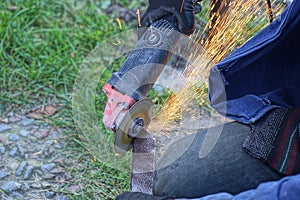 One worker in blue clothes cuts an iron rod with an electric grinder photo