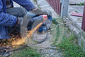 One worker cuts metal with an electric grinder with sparks