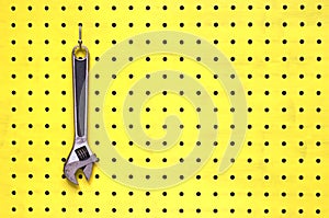 One wrench hangs from a hook on yellow pegboard