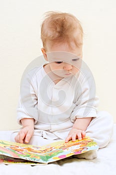 One year baby boy reads children's book