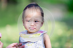 One year old Asian Baby Boy Makes a Serious Expression after Eating Sweet and Sour Strawberry Ice Cream, Child Wears an Apron.