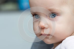 One year old baby gazes to the side with curious eyes. Concept of innocence and wonder in childhood