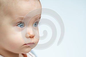 One year old baby gazes to the side with curious eyes. Concept of innocence and wonder in childhood