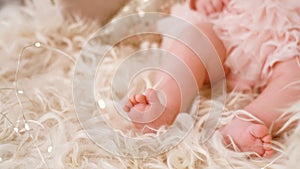 One-year-old baby lies on natural wool, the skin of the animal blond. Cute baby feet closeup of Christmas. Selective focus. a lot